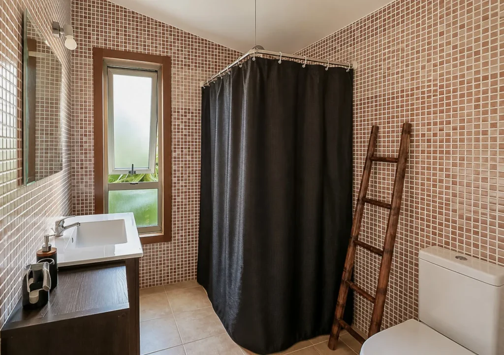 Baño completo con ducha, lavabo y ventana en la suit principal de O Igrexario Vacacional