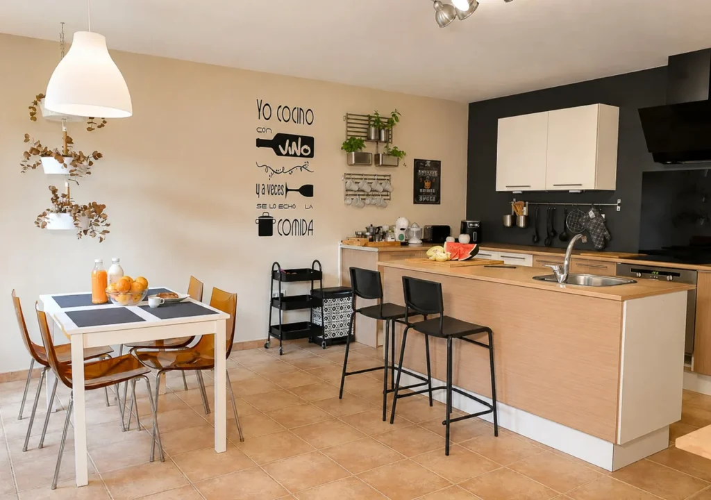 Cocina equipada con isla, dos taburetes y zona de comedor en O Igrexario Vacacional