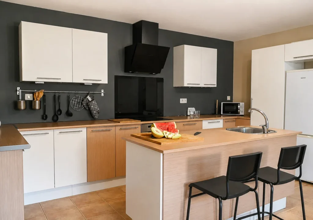 Cocina equipada con isla, fregadero y dos taburetes en O Igrexario Vacacional