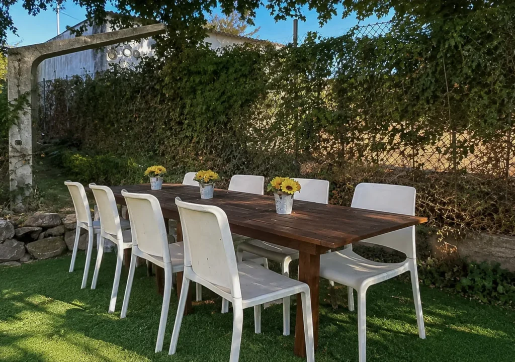 Comedor exterior con mesa grande rodeada de vegetación en el jardín de O Igrexario Vacacional