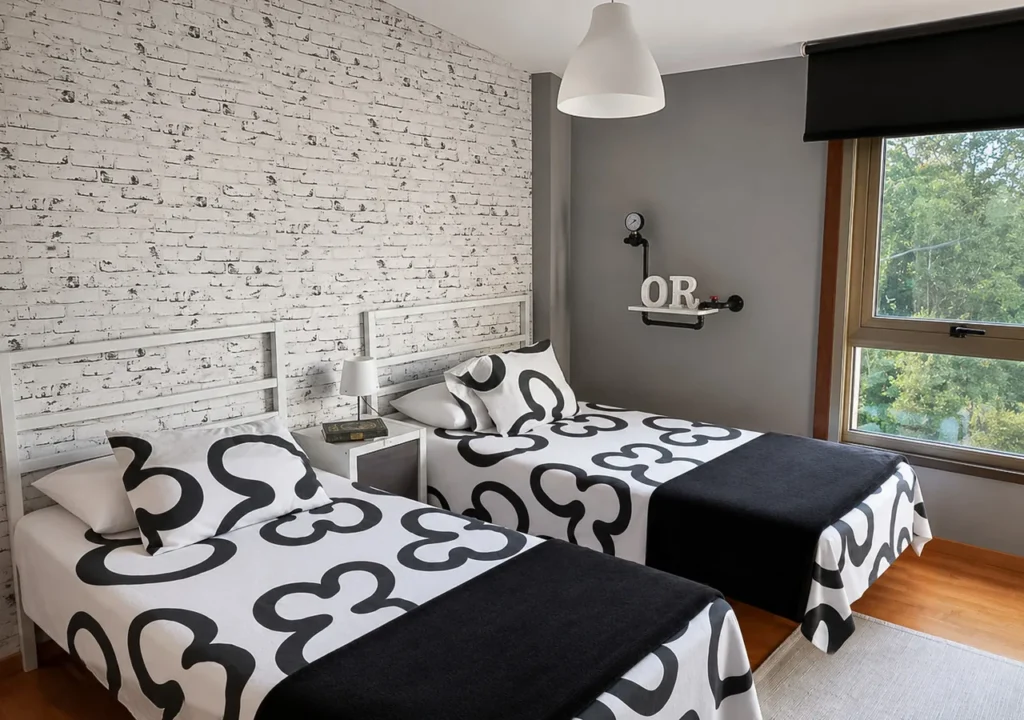 Dormitorio luminoso con dos camas individuales y ventana al jardín en O Igrexario Vacacional