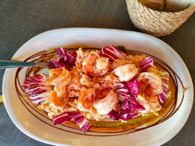 Ensaladilla cubierta con langostinos y hojas de achicoria en Kunkos Restaurante
