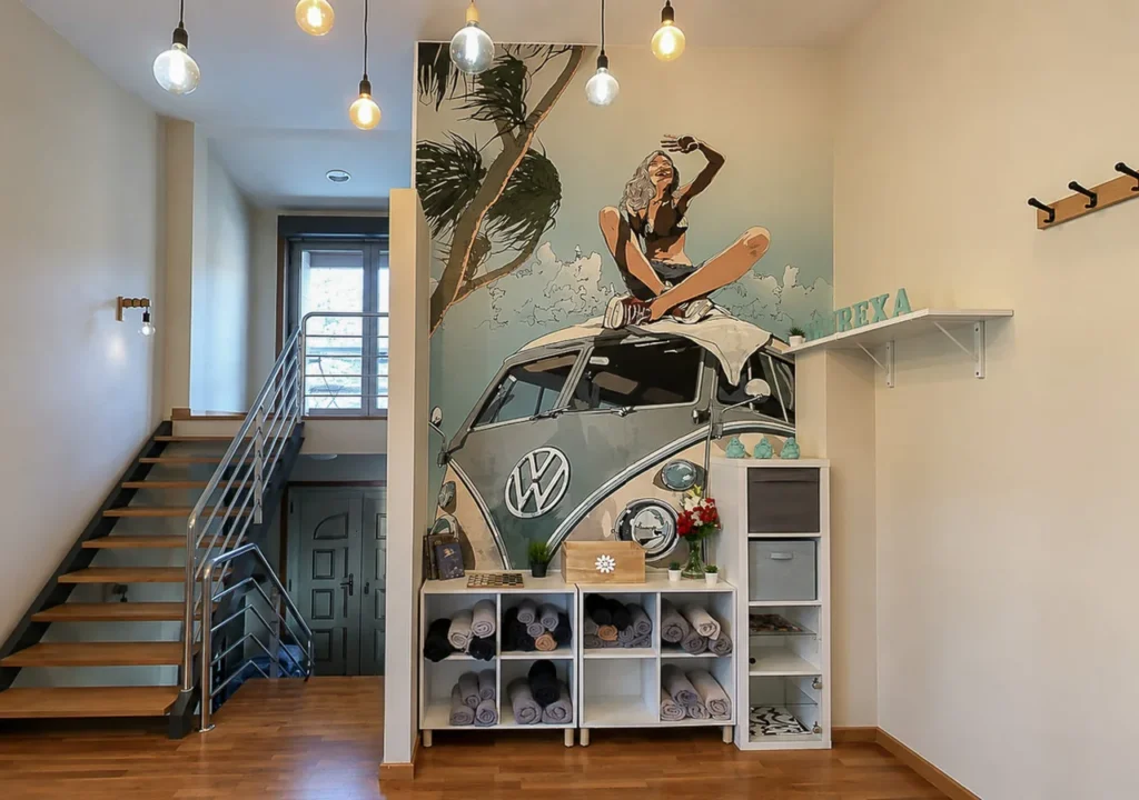 Entrada interior con escalera y mural de una furgoneta clásica en O Igrexario Vacacional