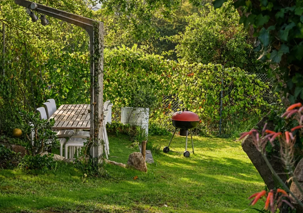 Jardín con barbacoa y mesa de comedor exterior en O Igrexario Vacacional