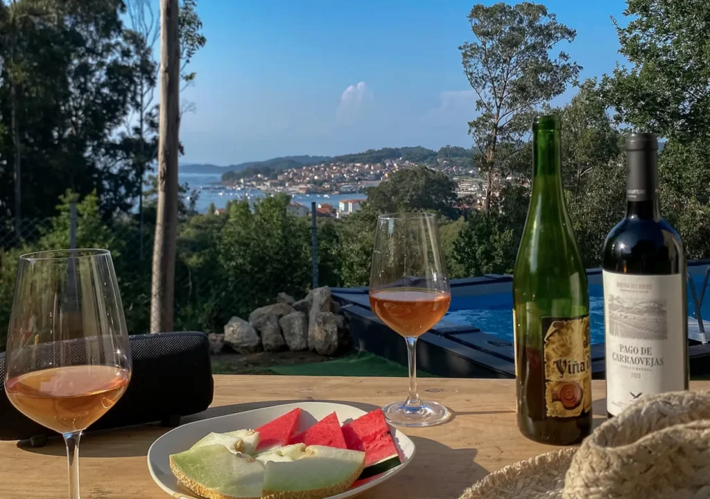 Mesa exterior con fruta y vino frente a la piscina y la ría de Aldán