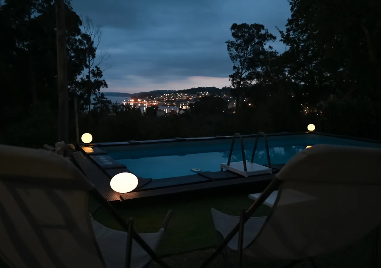 Reservas Piscina iluminada con tumbonas y vistas nocturnas a la ría de Aldán en O Igrexario Vacacional