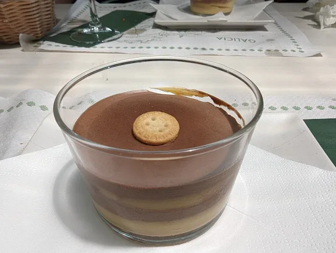 Postre de chocolate presentado en vaso con capas de crema y galleta