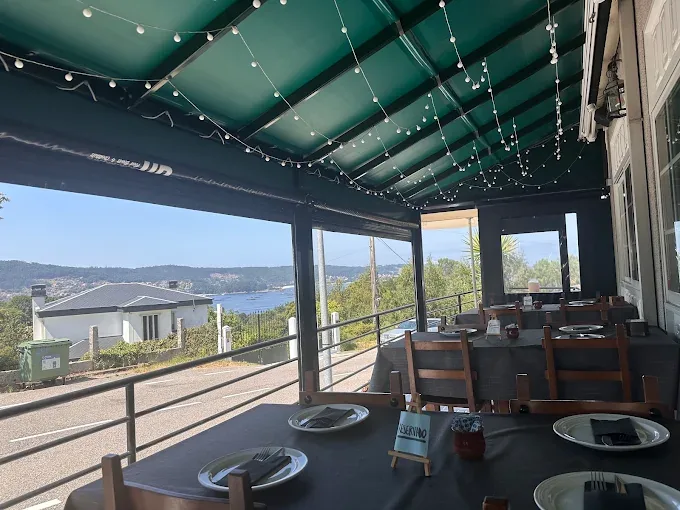 Terraza cubierta de Kunkos Restaurante con mesas preparadas y vistas a la ría de Aldán