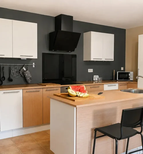Cocina equipada con isla, fregadero y dos taburetes en O Igrexario Vacacional