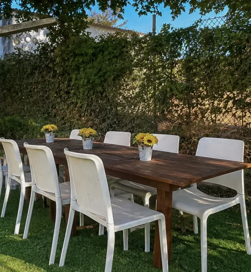 Comedor exterior con mesa grande rodeada de vegetación en el jardín de O Igrexario Vacacional